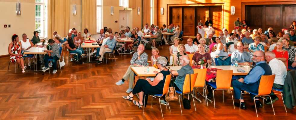 Ein Raum voller sitzender Menschen, manche sehen interessiert aus, wenige gelangweilt, ein paar daddeln auf dem Handy