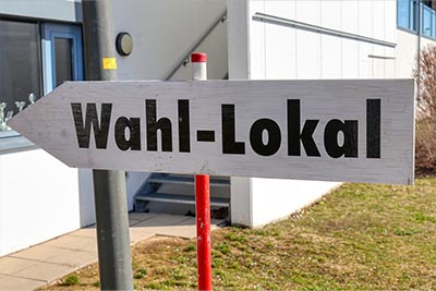 Schild in Pfeilform mit dem Text "Wahl-Lokal"